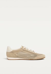 Chaussures de sport beige avec panneaux en mesh et accents en daim. Caractéristiques : bout rond, lacets plats et semelle basse en caoutchouc.