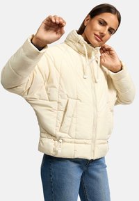 Puffy beige jacket with a high collar, front zipper, and drawstring hem. Features two side pockets and diagonal stitching patterns.