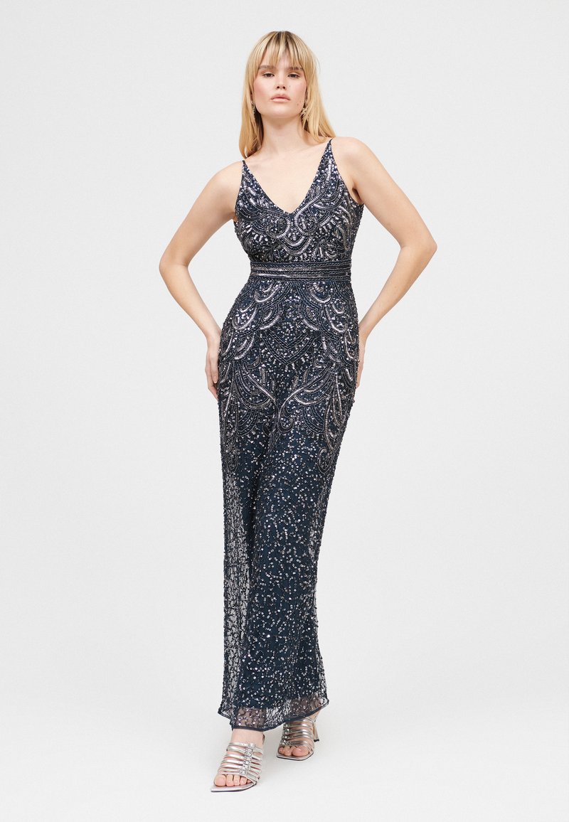 Abito da sera blu navy con perline, scollatura a V, lavorazione a perline intricata e silhouette aderente. Abbinato a tacchi a strappo argento.
