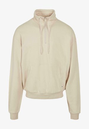 Kreemivärvi kootud pulli, millel on pool-lukuga kaelus, pikad varrukad, soonikkoes mansetid ja ees kangaroo tasku. Lihtne kangas, lõdvem istuvus.