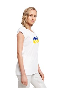 Weißes Baumwoll-T-Shirt mit einem blauen und gelben Grafikdesign sowie einem runden Emblem. Kurze Ärmel und lockere Passform.