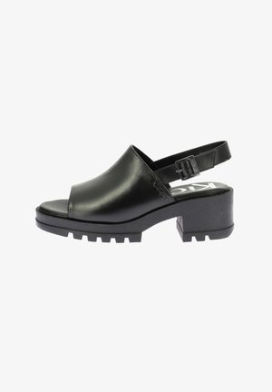 Sandalias de tacón de cuero negro con puntera abierta, correa ajustable en el tobillo y base de goma texturizada con detalle acanalado. Diseño de tacón plano.