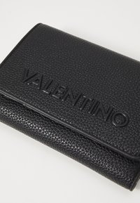 Portofel din piele neagră cu o textură distinctă, logo-ul embosat "VALENTINO" și un design elegant cu închidere tip rabatabil.