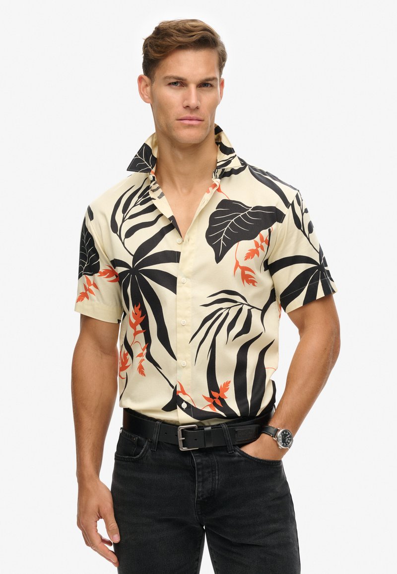Korte mouw shirt met een crèmekleurige achtergrond, voorzien van grote zwarte en oranje tropische bladmotieven en een knoopsluiting kraagontwerp.