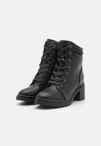 Black lace-up ankle boots made of smooth leather, featuring a chunky heel, rubber sole, and side knit accents.