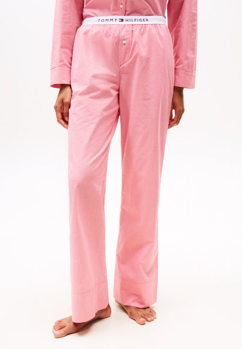 Pantalon de pyjama rose clair avec un motif à carreaux, doté d'une taille élastique blanche avec le logo "Tommy Hilfiger" et d'une coupe décontractée.