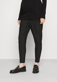 Svartstripete bukser med slim fit og myk stoff, kombinert med skinnende svarte loafers med en dekorativ spenne.