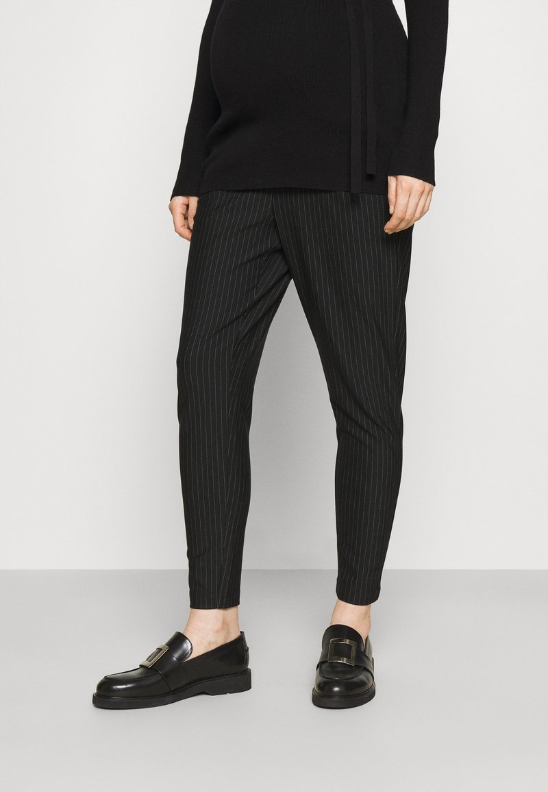 Svartstripete bukser med slim fit og myk stoff, kombinert med skinnende svarte loafers med en dekorativ spenne.