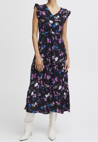 Abito lungo nero con fiori, dotato di maniche a balze, con fiori bianchi, rosa e blu. Realizzato in tessuto leggero, design a strati e scollatura a V.