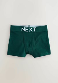Gröna bomullshorts med vit elastisk midjeband där ordet "NEXT" är tydligt avbildat. Slät textur och åtsittande design.