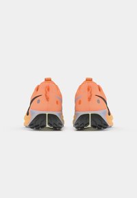 Heldere oranje sport schoenen met een textuur bovenkant, zwarte accenten en een uniek patroon op de zool. Voorzien van trekflappen voor gemakkelijk aan- en uittrekken.