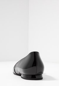Svart lackläderballetskor med rund tå, lätt klack och rena sömmar. Slät, glänsande yta med en sömlös design.