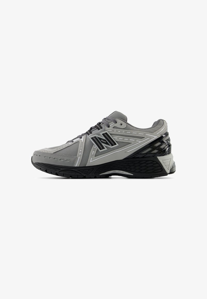 Chaussure de sport grise et noire avec dessus en mesh, semelle épaisse et rembourrée, et logo New Balance sur le côté, présentée de profil sur fond blanc.