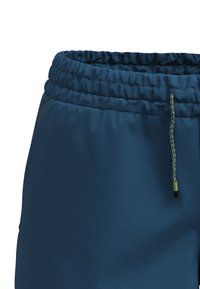 Mörkblå sweatpants har ett texturerat elastiskt midjeband med dragsko, accentuerat med en grön och svart snodd. Sidofickor är synliga.
