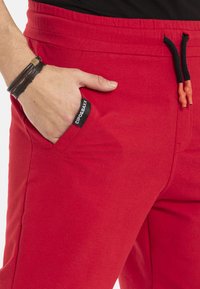 Rode sweatpants van katoenmix, met elastische tailleband, trekkoord met zwarte punten, zijzak met merkembleem.
