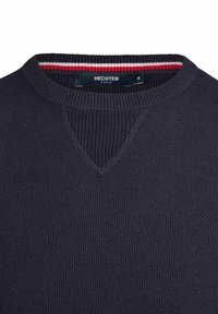Dunkelblauer Strickpullover mit Rundhalsausschnitt, der ein strukturiertes Muster und einen kontrastierenden rot-weißen Streifenakzent am Kragen aufweist.