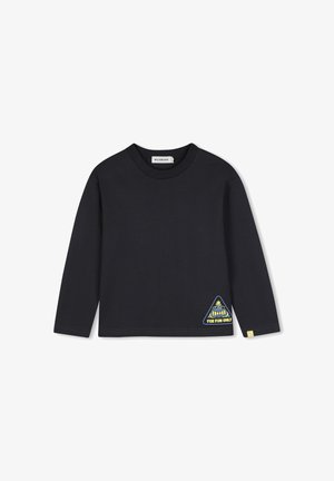 Zwarte longsleeve met ronde hals met een klein driehoekig labeltje vlak bij de onderzoom met een cartoongezicht en tekst "For Fun Only."