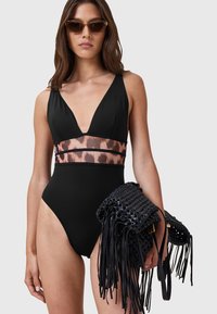 Sort ét enkelt swimsuit med dyb V-udskæring og leopardprint bånd i taljen. Modellen holder en sort vævet taske med frynser.