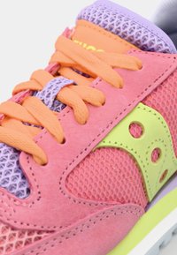 Lyserøde suede sneakers med mesh-paneler, orange snørebånd og en limegrøn detalje. Har lilla og grå nuancer på tungen og sålen.