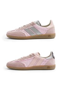 Paire de baskets basses en daim rose et tissu avec semelles en caoutchouc, lacets à l'avant et bandes métalliques et pastel contrastées sur les côtés.