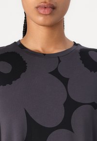 Short-sleeved gray t-shirt in soft fabric featuring a black abstract pattern. Round neckline with a smooth texture. No visible branding.