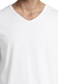 White v-neck t-shirt made of lightweight cotton. Features a smooth texture with a relaxed fit and subtle stitching around the neckline.
