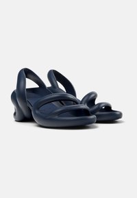 Navy blue sandals made of flexible material, featuring curved straps and sculpted sole for modern design. Open-toe style with minimal accents.