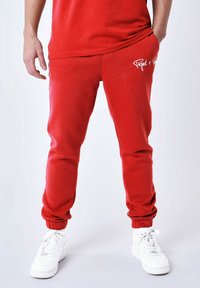 Rode sweats met ribgebreide manchetten, zijzakken en witte logo-details. Gemaakt van zachte stof, ontworpen voor comfort en casual gebruik.