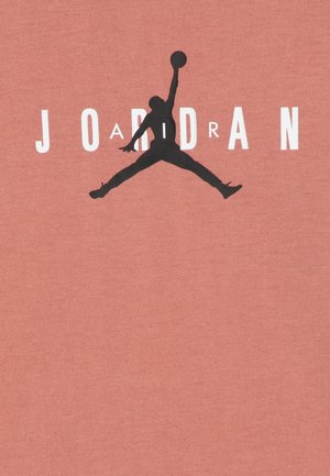Camiseta de algodón en color coral que presenta una silueta negra de un jugador de baloncesto y el texto "JORDAN" en letras blancas.