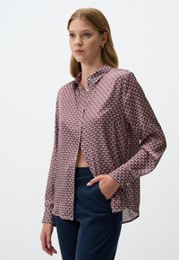 Langärmliges Hemd mit einem geometrischen Muster in Rot, Weiß und Blau. Mit einem Kragen und einer knopfverzierten Vorderseite. Leichter Stoff.