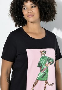 Czarny t-shirt z krótkim rękawem z grafiką lamparta w zielonej sukience na różowym tle, z napisem "NORMALNE JEST NUDNE."