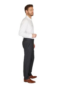 Dunkelgraue Hose aus einem strukturierten Stoff, mit geradem Schnitt und einer Gesäßtasche, getragen mit einem weißen Hemd mit Kragen und braunen Schuhen.
