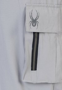 Light gray fabric with a side zip pocket and a gray spider graphic. The zipper is highlighted, contrasting with the smooth texture of the material.