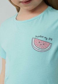 Lichtblauwe katoenen T-shirt met een ronde hals, met een watermeloenafbeelding en de tekst "verzoet mijn dag" erboven.