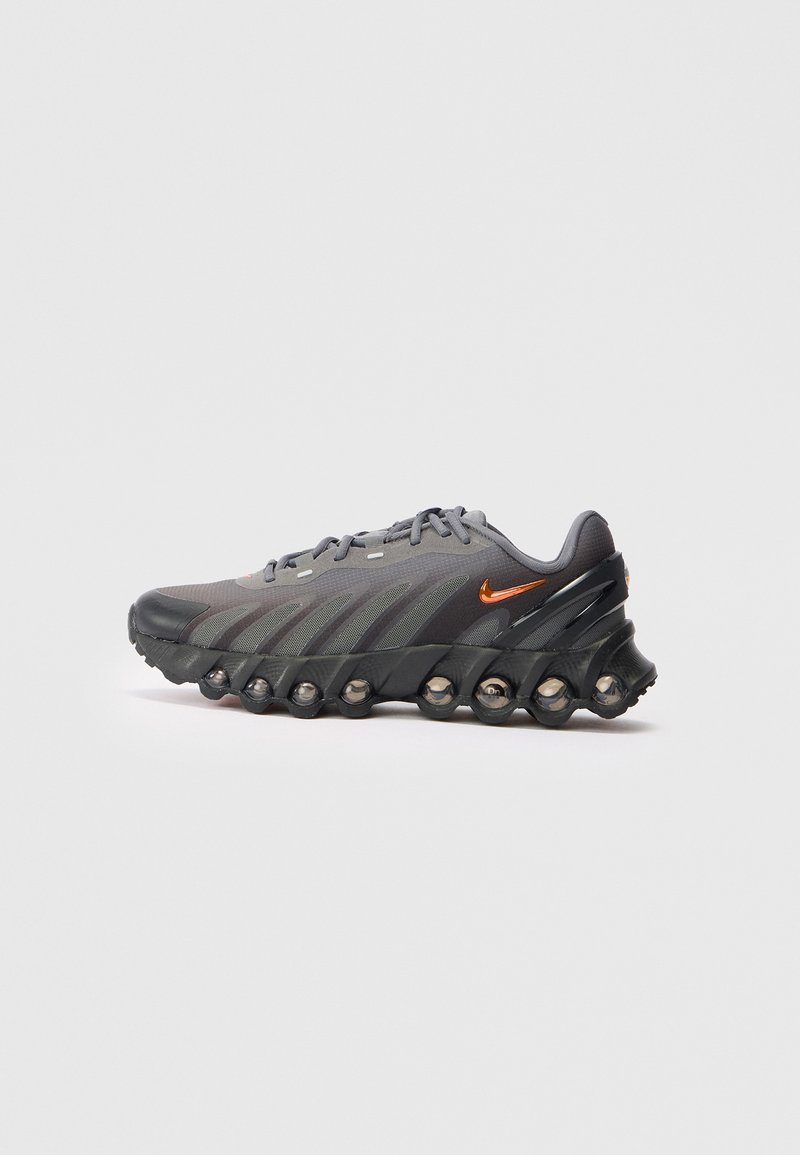 Tamsiai pilki sportiniai bateliai su juodupadu, pasižymintys matomais oro pagalvėlėmis ir mažuoju oranžiniu Nike logotipu šone.