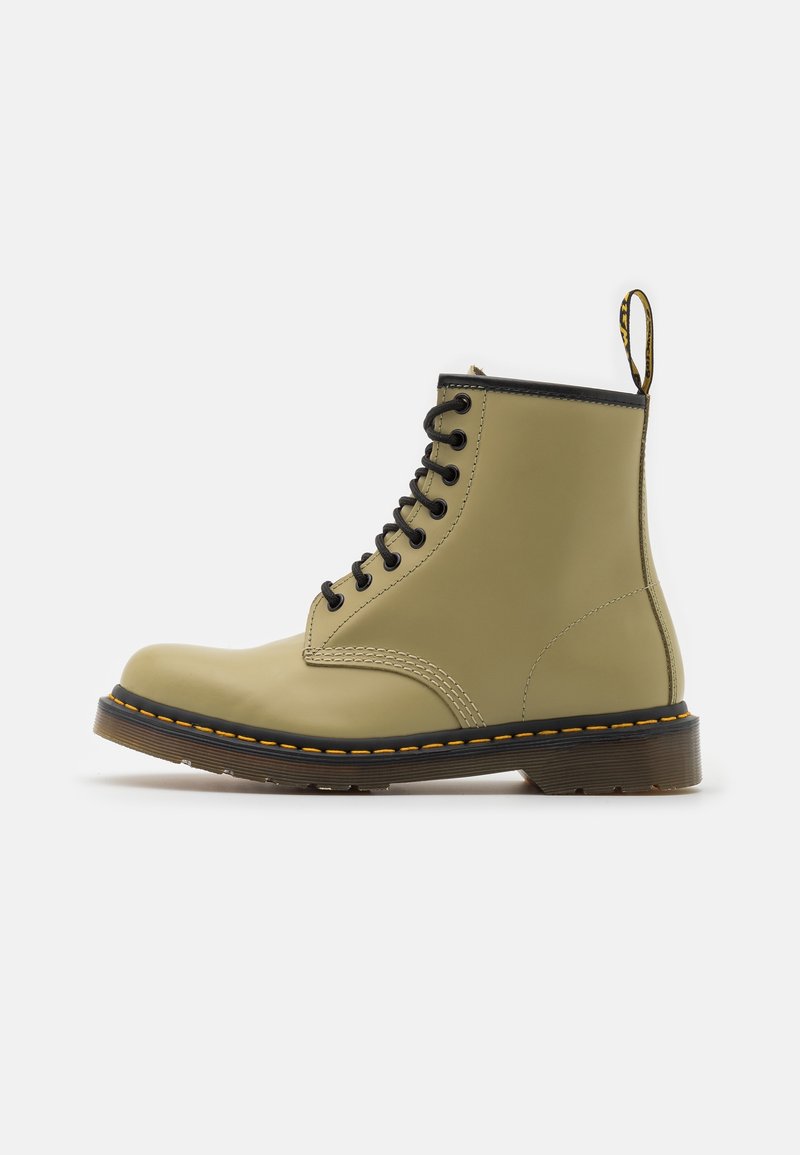 Bottine beige en cuir à lacets avec semelle noire, couture jaune et languette à l’arrière, présentée en profil latéral sur fond blanc.