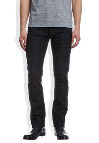 Vaqueros de mezclilla azul oscuro con corte ajustado, que cuentan con cinco bolsillos y una textura suave, combinados con botas de cuero negras hasta el tobillo.