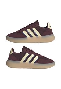 Paire de baskets Adidas bordeaux avec bandes crème et semelles beiges translucides présentées côte à côte sur fond blanc.