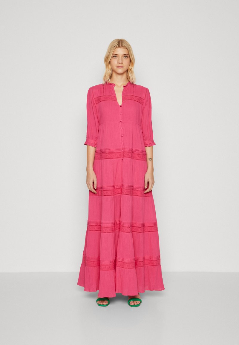 Vestido longo rosa feito de tecido leve, com fechamento frontal em botões, mangas três quartos e detalhes texturizados em acentos horizontais.
