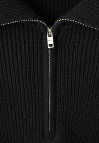 Maglione nero a coste con colletto alto e zip argentata. Presenta un tessuto testurizzato e un design minimalista. Vista ravvicinata.