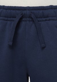 Mörkblå bomulls sweatshirt med ett elastiskt midjeband och dragsko. Har ribbad textur och sömdetaljer runt midjan.