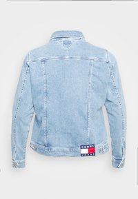 Chaqueta de mezclilla azul claro con mangas largas, cuello clásico y costuras resaltadas. Cuenta con un parche azul marino con "TOMMY JEANS" en la parte trasera.