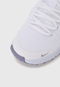 Valge spordijalgpall king, millel on tekstuuriga võrkkangas ülemine osa, kergete lillakate aktsentidega ja hall Nike logo küljes. Paelad on valged ja siledad.