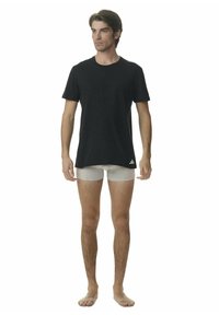 Czarny bawełniany t-shirt z okrągłym dekoltem, w połączeniu z jasnoszarymi dopasowanymi slipami. T-shirt ma małe białe logo na dolnym brzegu.