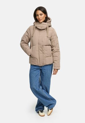 Beige puffer jacket with a high collar, front zipper, and drawstring hood; paired with wide-leg blue denim jeans and casual shoes.