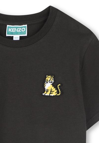T-shirt en coton noir avec un tigre brodé jaune et blanc sur la partie gauche de la poitrine, avec un col rond et des manches courtes.
