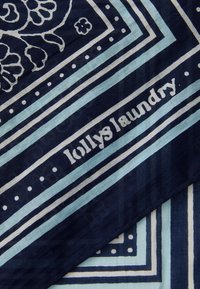 Modrá a námornícka šatka s kvetinovými vzormi, pruhmi a bielymi akcentmi. Obsahuje text "lollyslaundry" v neformálnom písmovom štýle. Materiál: bavlna.