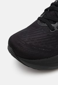 Black running shoe with a textured, woven upper, lace closure, and a cushioned, curved sole, featuring subtle branding on the side.