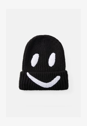 Beanie lavorato a maglia nero con risvolto, caratterizzato da un design di faccina sorridente bianca in peluche. Struttura a costine su tutto il cappello per un calore aggiuntivo.