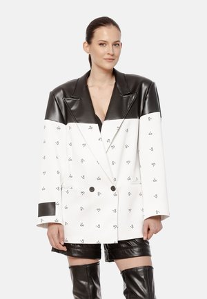 Dwurzędowa marynarka w białym i czarnym sztucznym skórze, z dużym kołnierzem, powtarzającym się czarnym wzorem logo oraz dwoma przednimi kieszeniami.